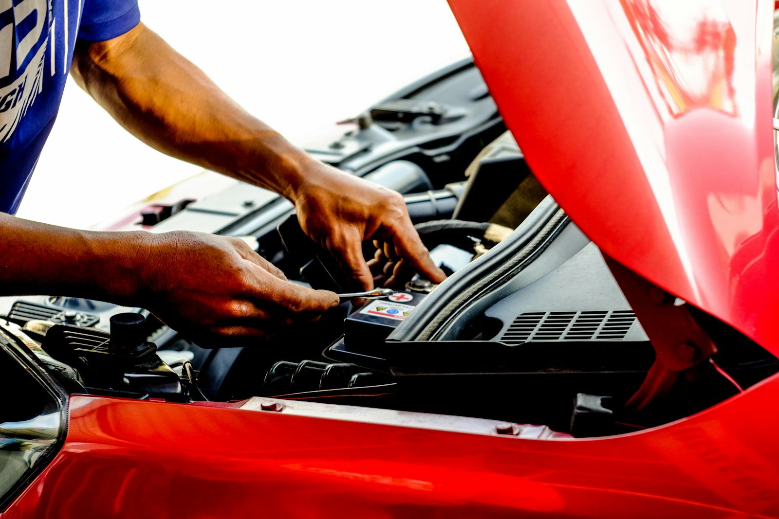 Manos instalando una batería en el compartimiento del motor
